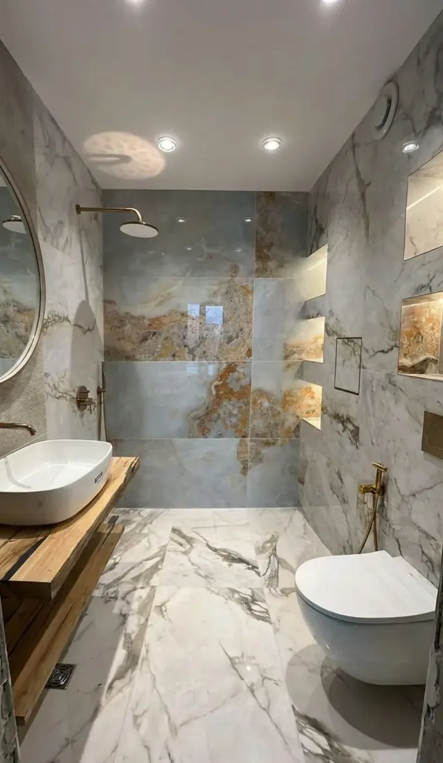 The same bathroom after the renovation: marble-look tiles, a basin on a wooden top, a wall-hung toilet