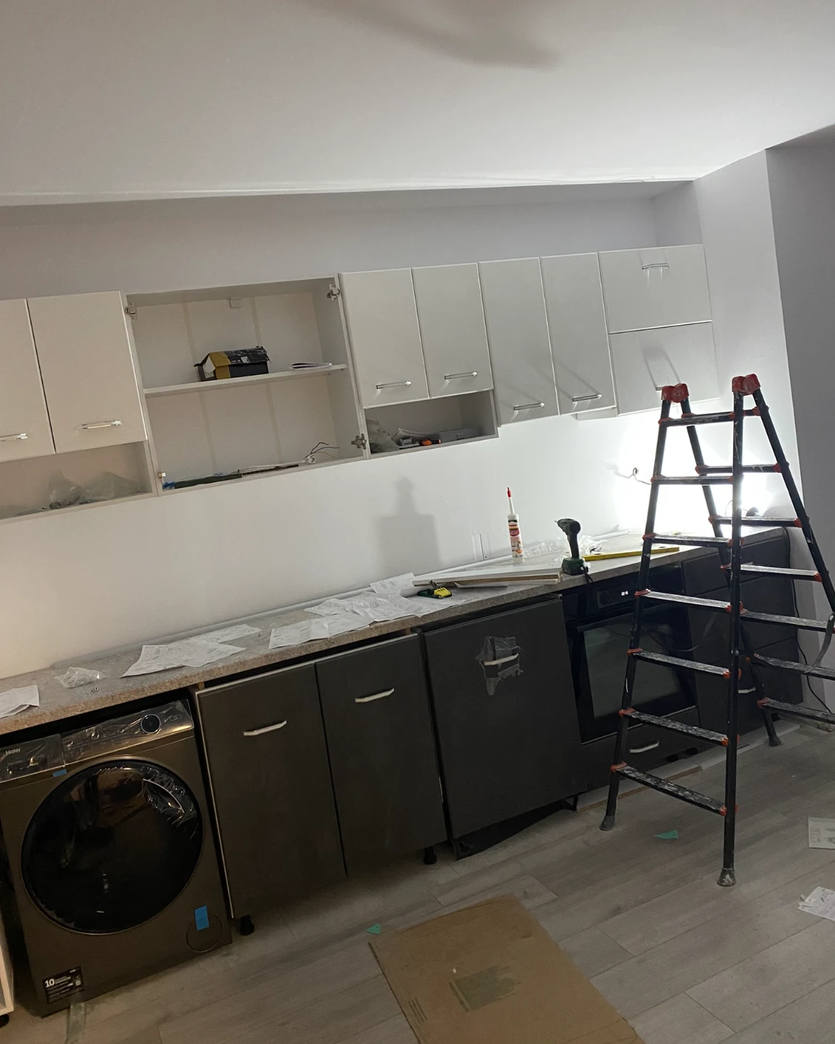 Fitting the kitchen cabinets: open wall units, a stepladder, the worktop being finished